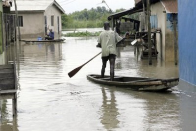 Men canoe to their homes during flooding in Nigeria.