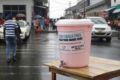 A large bucket of chlorinated water on the street of central Monrovia for passersby to wash their hands.
