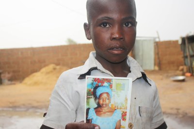 A boy holds up a photo of his 19-year-old sister, Deborah Solomon, one of the schoolgirls kidnapped by Boko Haram militants.