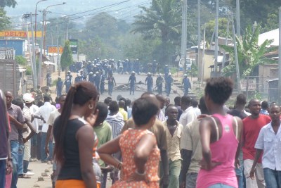 Police look on as people demonstrate in Bujumbura against a decision by Burundi's ruling party to nominate President Pierre Nkurunziza to run for a third term in elections slated for June 2015.