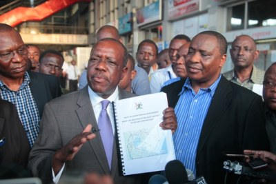 Energy and Minerals Professor Sospeter Muhongo briefs reporters on arrival at the Julius Nyerere International Airport in Dar es Salaam from Kampala, Uganda. Right is the Permanent Secretary in the ministry, Professor Justin Ntalikwa, while left is the general Director of the Tanzania Development Petroleum Corporation, Dr James Mataragio.