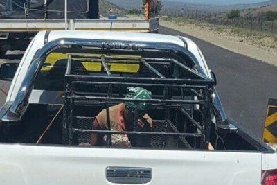 Image of the woman sitting in the cage on the back of the truck.