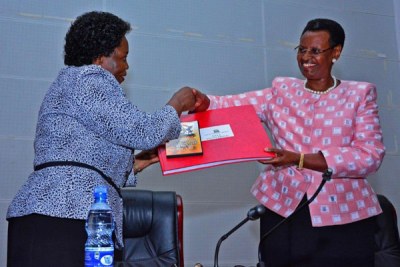 Mary Okwakol, Uganda National Examinations Board Executive Secretary(left) hands over the results handbook to First Lady Janet Museveni.