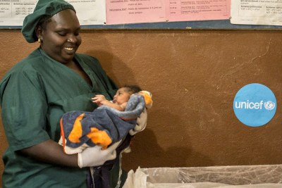 Midwife Fadimata Maïga holds a newborn infant before placing it beneath an infant radiant warmer in order to proceed to a newborn health assessment at the Baraouéli Health Center in Baraouéli, Ségou region, Mali.