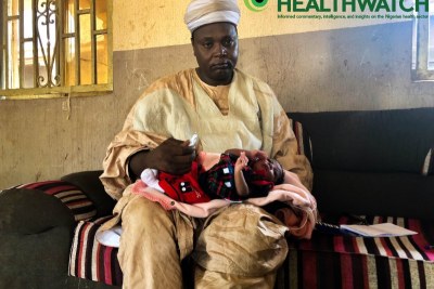 Sarkin Gagi, Alhaji Umar Jabbi with his newborn baby. In his hand is a Chlorhexidine gel which is being applied on the boy's unbiblical cord area.