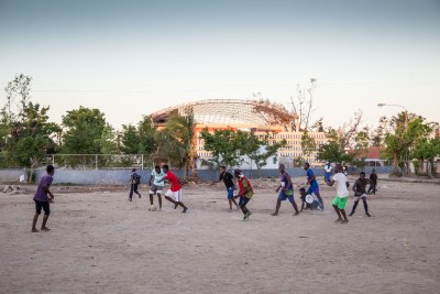 Young boys play soccer in Beira, Mozambique in May 2019. In the background stands Macuti Catholic Church with its roof destroyed by Cyclone Idai.