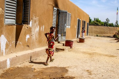 A girl runs outside a small community school in Korioume, Mali, where children lack basic equipment, including notepads and pens. Parts of the school have been attacked and in 2013 the village was a Jihadist stronghold.